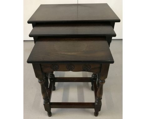 A dark wood nest of 3 tables with vintage rose carving to sides and turned detail to legs.