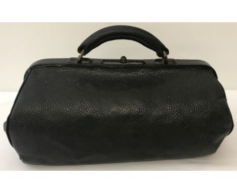 A vintage Gladstone bag in black leather with metal feet to base.