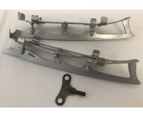 A pair of vintage metal ice skate shoe attachments with adjusting key.