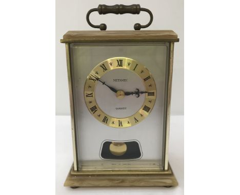 A quartz movement Metamec pendulum carriage clock. With roman numeral markers on a gilt rimmed face. Approx. 19.5cm tall to t