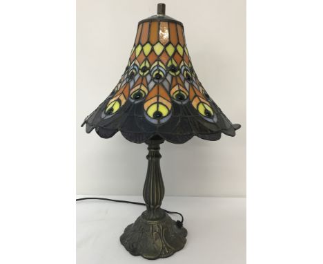 A Tiffany style vintage lamp with peacock feather decoration to shade.In terracotta, peach and yellow colourway. On cast meta