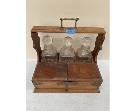 An oak triple decanter stand fitted with lidded compartments and drawer