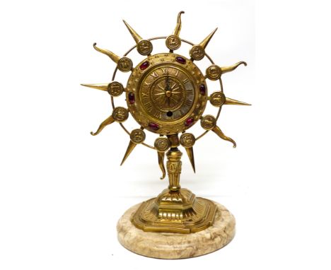 Gilt metal clock, the face inlaid with red stones bordered by symbols of the Zodiac, clock mounted on a circular slate base, 