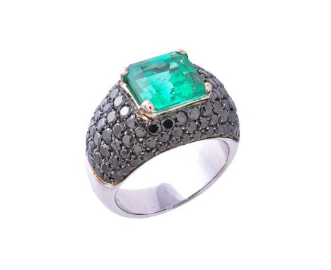 An emerald and black diamond ring, the square cut emerald, estimated to weigh 4.00 carats, in a four claw setting, within a s