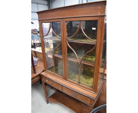 An Edwardian mahogany display cabinet on stand having glazed top with velvet lined shelves, two frieze drawers and shaped und