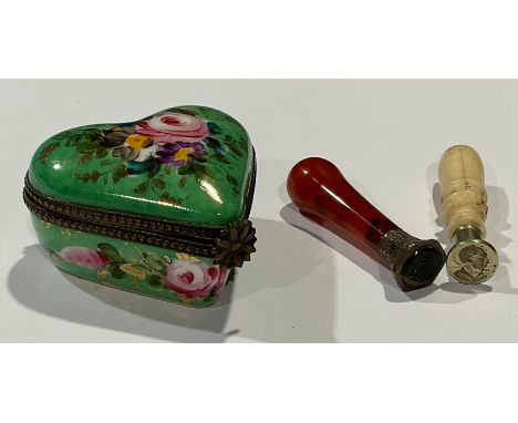 A 19th century carved bone seal, 4.5cm; a 19th century polished carnelian wax seal, 4.5cm; a Limoges love heart shaped patch 