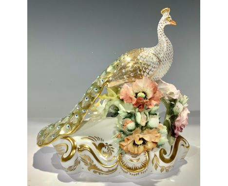 A Royal Crown Derby Peacock, perched upon a bough encrusted with flowers, scroll base, printed mark in red, 17cm high 