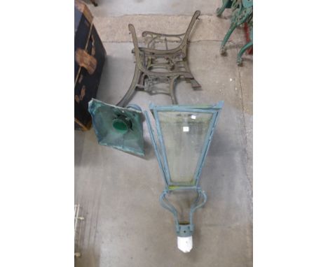 A copper and steel lantern and a pair of cast iron bench ends