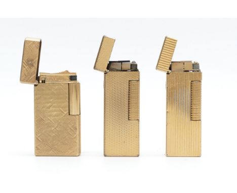 Alfred Dunhill; A gold plated Dunhill '70' gas cigarette lighter, together with two Dunhill rollagas examples, having engine 