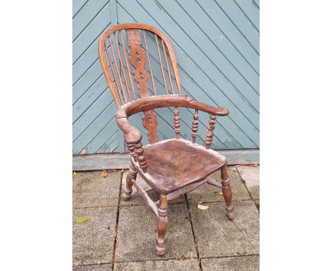 An oak and elm Windsor armchair having pierced heart and clover detailing to backrest, the saddle seat with bobbin turned arm