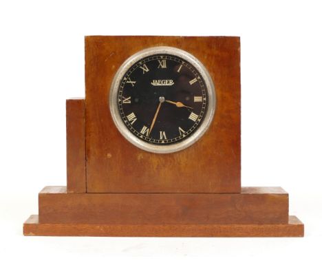 A Jaeger car dashboard clock, black dial with Roman numerals, keyless movement with winding stalk, fitted into an oak mount, 