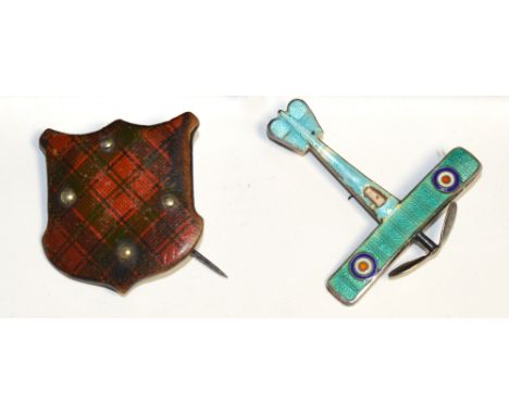 A yellow metal brooch in the form of a Scottish clan tartan shield and a silver and enamel bi-plane (2).