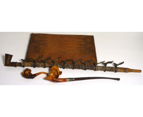 An African senufo or bamoum pipe, the wooden stem set with snakeskin and alternating brass antelope and bird heads rings, two