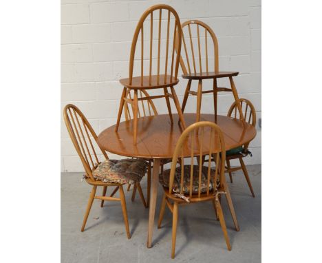 A retro Ercol oval dining table, length when extended 124cm, with four matching stick back dining chairs and two smaller Erco