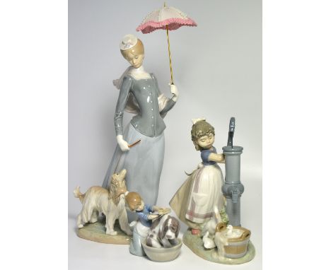 Three Lladro figure groups, compromising a large example depicting a lady with an umbrella walking a spaniel, one depicting a