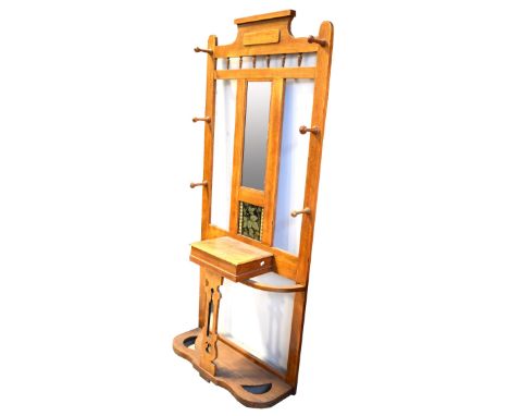 An early 20th century oak Arts and Crafts hall stand, the rectangular mirror with tile beneath decorated with leaves and foli