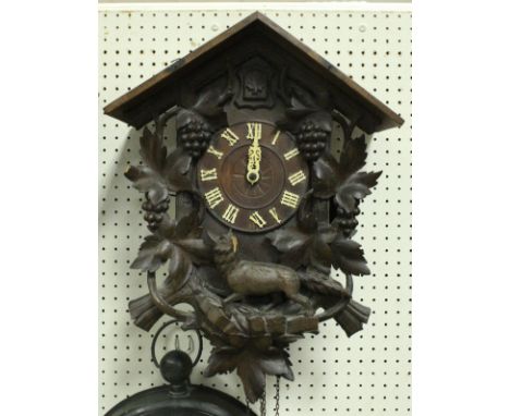 An early 20th Century carved wooden cased cuckoo clock decorated with grape and vine and running wolf
