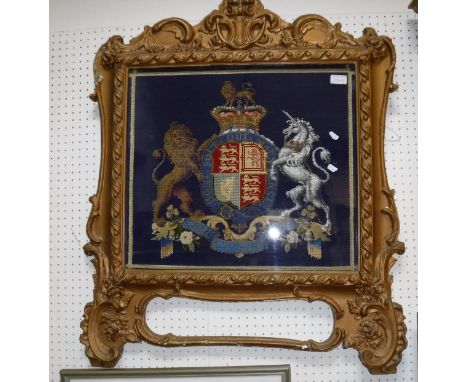 A Victorian giltwood and gesso framed fire screen/wall panel needlework decorated with a Royal coat of arms on a blue backgro