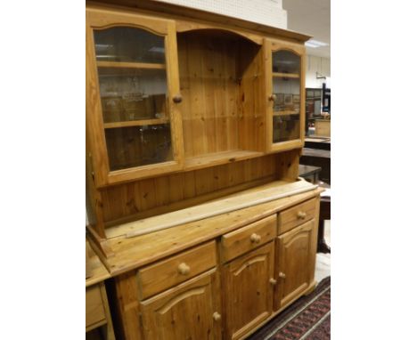A modern pine dresser with two glazed doors above three drawers and three cupboard doors to bracket feet