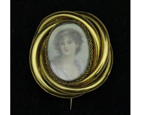 A gold coloured brooch with miniature portrait study of a young woman with band in her hair, bearing label inscribed verso "P