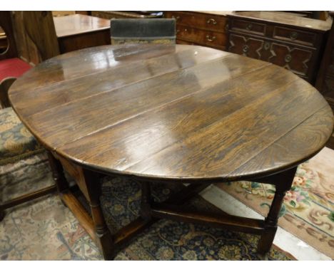 An oak oval gate-leg drop-leaf dining table in the 18th Century manner, with single end drawers on turned and ringed legs uni