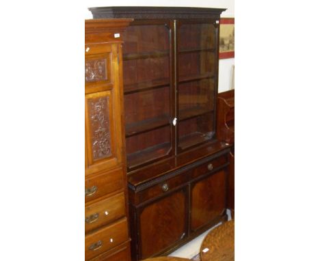 A mahogany bookcase in the Chippendale taste with two glazed doors enclosing four shelves on a base of two drawers and two cu