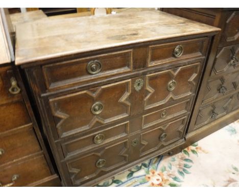 An oak chest in the Jacobean taste, the plank top over four long drawers with applied moulded decoration and brass ring handl