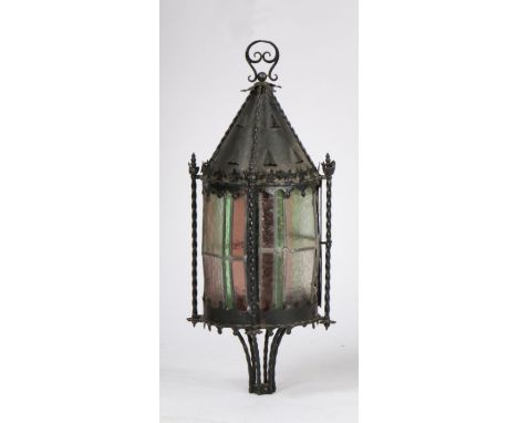 Ecclesiastical style hanging lantern, with a cone top above fleur de lis finials above the coloured glass body, 68cm high
