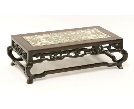 A Chinese hardwood stand,late Qing dynasty, pierced and carved with a stylised chilong apron and shaped legs, the top inset w
