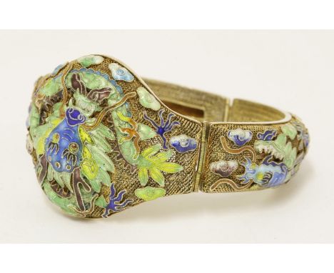 A Chinese silver gilt hinged bangle,1930s, the mesh ground decorated with dragons amongst clouds in coloured enamels, stamped