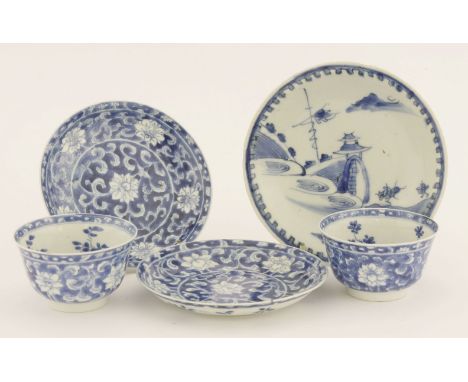 A pair of Chinese porcelain blue and white tea bowls and saucers,Kangxi (1662-1722), painted with flowers on a blue ground, t