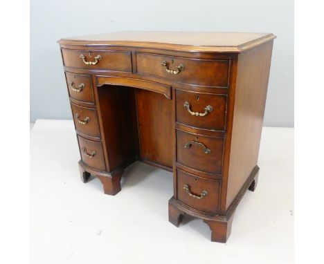 A mahogany serpentine fronted kneehole writing desk with eight drawers, central cupboard and raised on bracket feet. Overall 