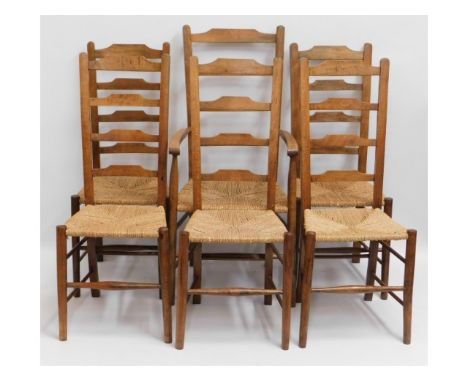A set of six 20thC. rush seated oak ladder back chairs including one carver, 44.5 high to back