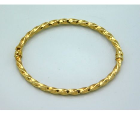 A yellow metal twist effect bangle, tests electronically as 9ct gold, 61mm diameter, 3.9g