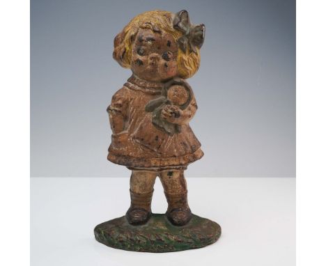 This charming antique cast iron doorstop features a young girl clutching a doll, with endearing facial details and a large bo