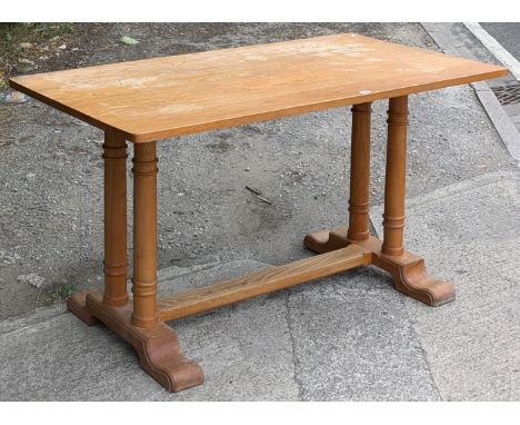 A light oak dining table with a rectangular top, &amp; on a pair of turned supports to either end joined by a plain centre st