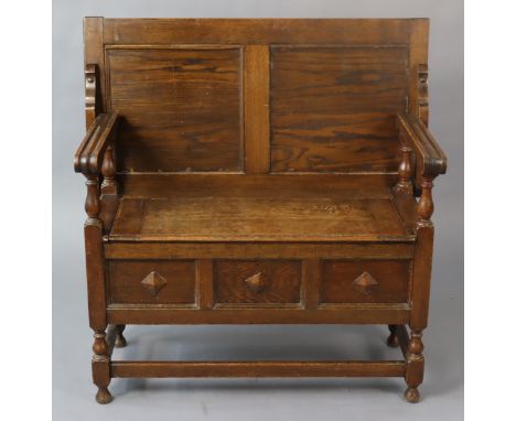 An oak monks-bench with a rectangular fold-over top, having a hinged box-seat, with panelled front &amp; sides, &amp; on shor