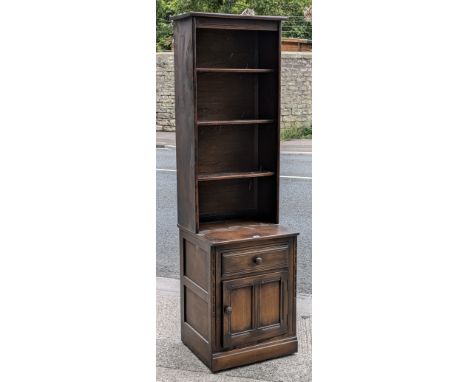 An Ercol dark oak tall standing wall unit fitted three open shelves to the top, above a long drawer &amp; with cupboard below