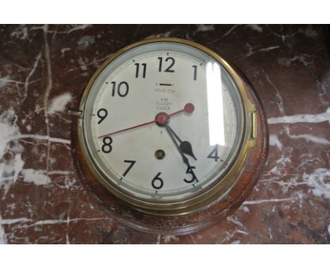 A brass Military bulkhead clock by Elliott no 0552/724 on a mahogany mount with 6 inch dial - working in the sale room - gene
