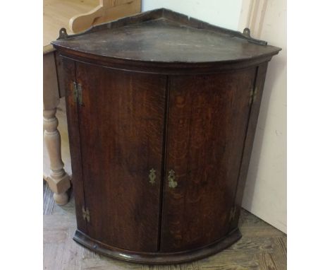 A Georgian Oak bow front three shelf hanging corner cabinet