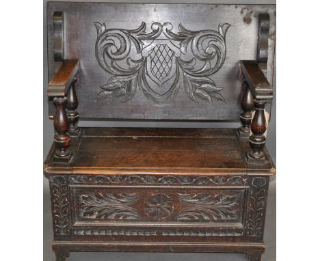 A 17th century style monk's bench, the carved rectangular top with turned supports above a hinged seat, W. 92cm.