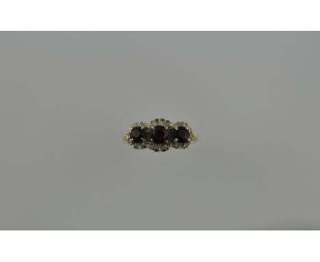 A three stone ruby ring, in a diamond setting, on an 18ct yellow gold band, 4g.