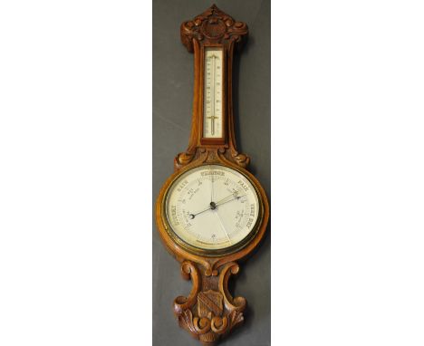 An early 20th century oak aneroid barometer, the foliate carved case incorporating a thermometer. 