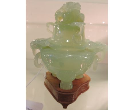 A Chinese carved jade koro and cover with ring handles on three paw feet with brass inlaid hardwood stand.