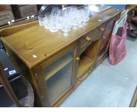 A pine dresser base; with two glass panelled doors; flanking an open shelf unit