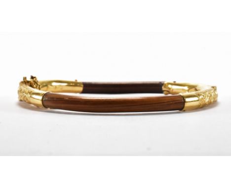 A Chinese gold and wooden bangle bracelet. The bracelet of wooden construction with gold banding having incised decoration, w
