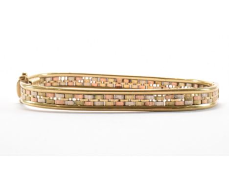 A hallmarked 9ct gold tri tone bangle bracelet. The bracelet of woven design with a hinged opening and tongue in groove clasp