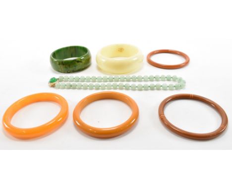 A group of vintage 1930s early plastic / bakelite bangles to include a green and orange bangle bracelet, a pair of orange ban