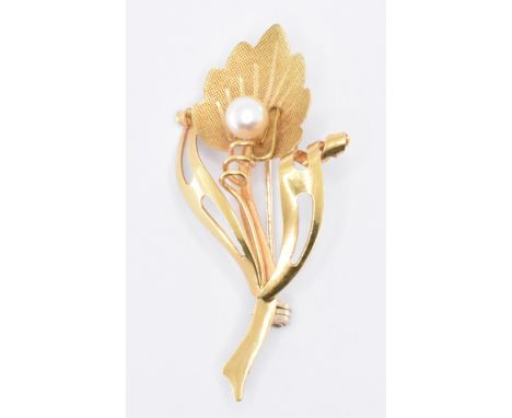 A gold and pearl floral brooch. The flower brooch being set with a single pearl, with a hinge pin and roller clasp to the ver