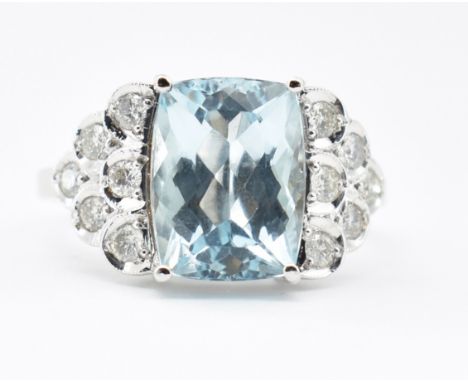 An Art Deco style aquamarine and diamond ring. The ring set with an octagon step cut aquamarine flanked by diamond set scale 